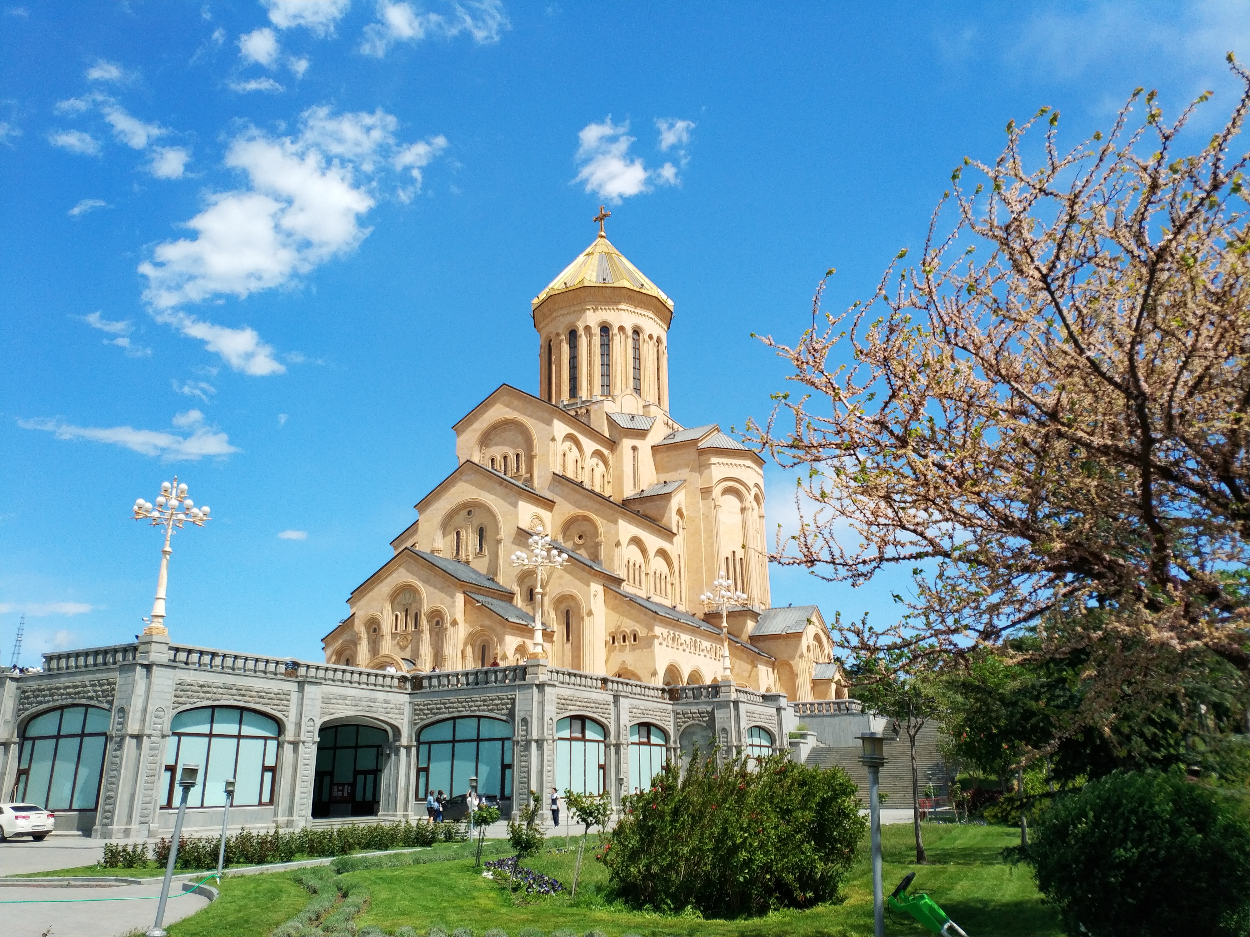 გარე ფასადი — ქვის მოსაპირკავე, მოხეტიალე თაღები და სამების საკათედრო ტაძრის ოქრირებული ცენტრალური გუმბათი